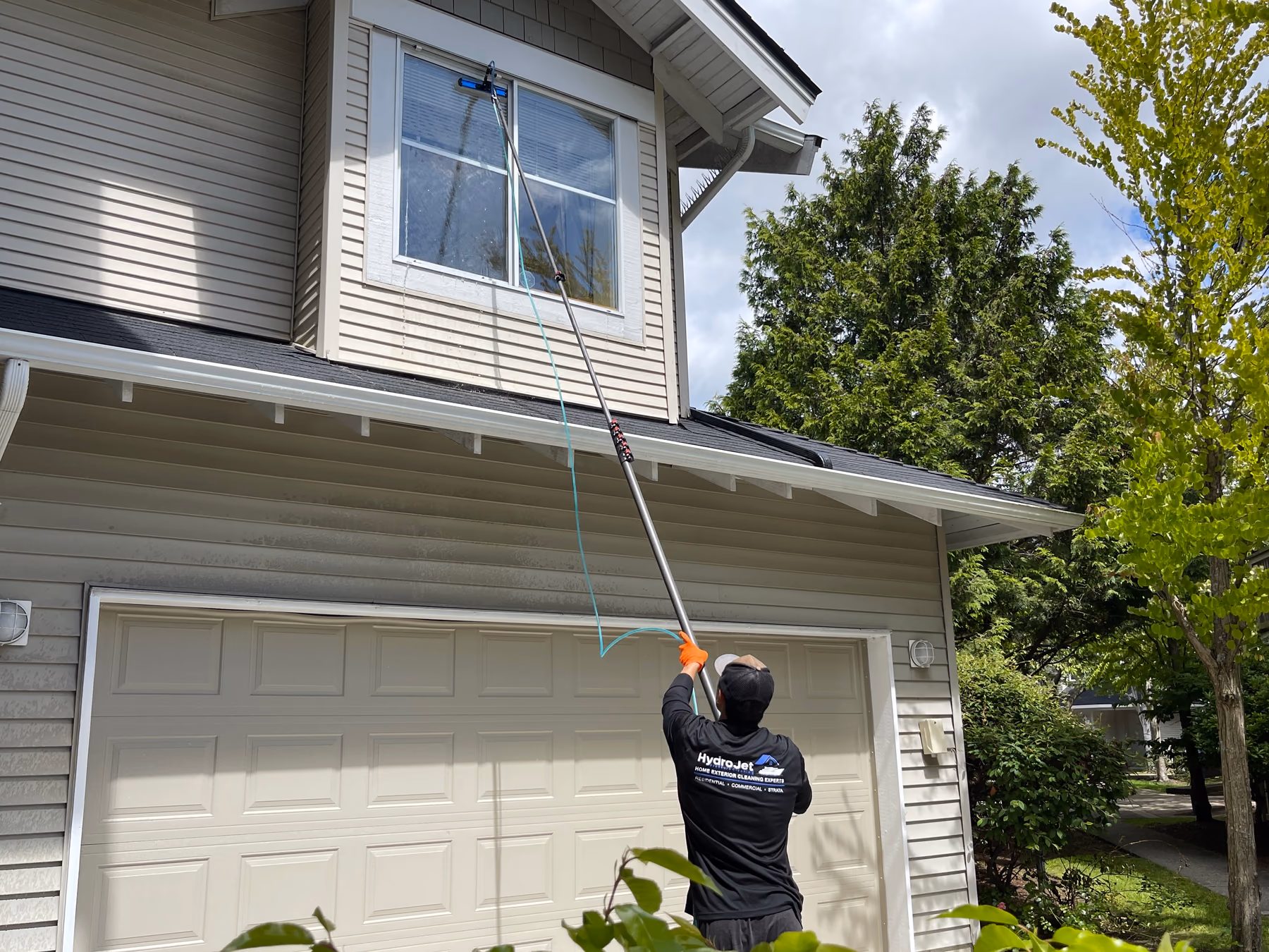 HydroJet crew member cleaning second-storey windows with a water-fed pole